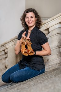 Das Portrait von Anita Brunner-Irujo zeigt sie auf den Stufen sitzend. Sie hält ihre Tanzschuhe in der Hand