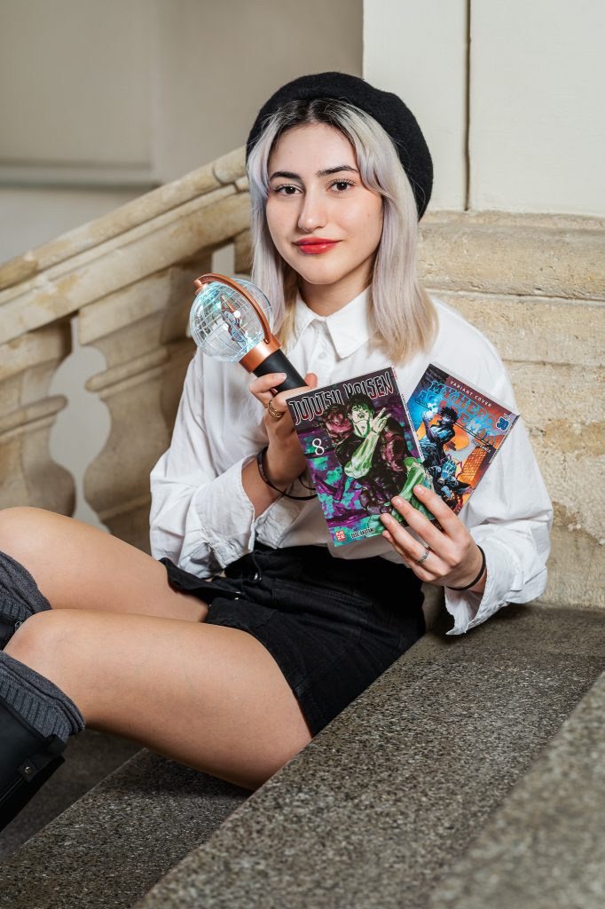 Das Portrait von Saidat Talkanova zeigt sie auf den Stufen im Stiegenhaus sitzend. Sie hält Mangas in der Hand.