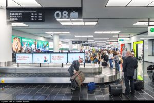 Viele Menschen warten beim Kofferband am Flughafen auf ihr Gepäck